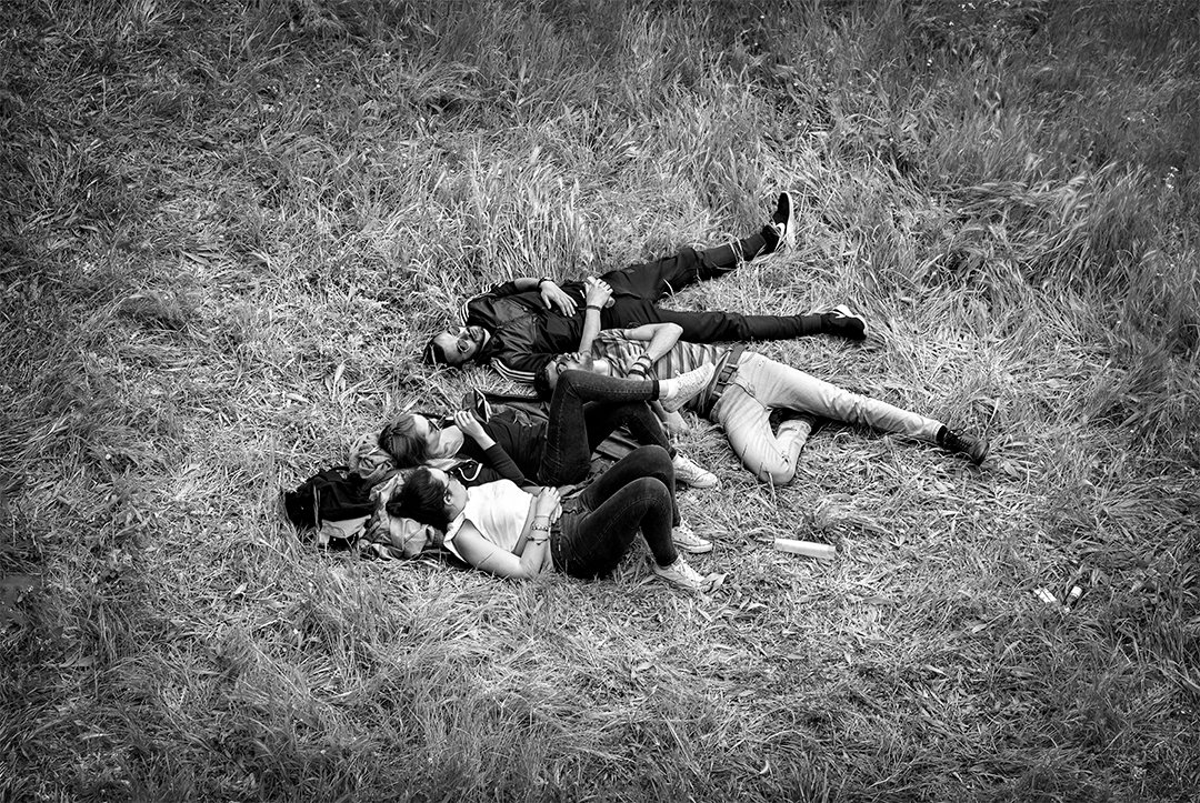 Several people lying together on a grassy slope.